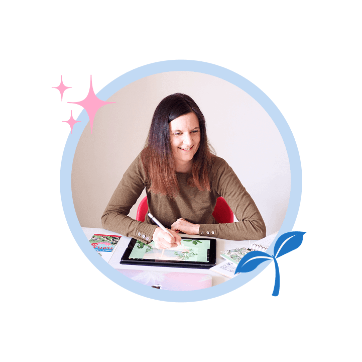 Photo of me smiling while working at my desk with design tools and a laptop